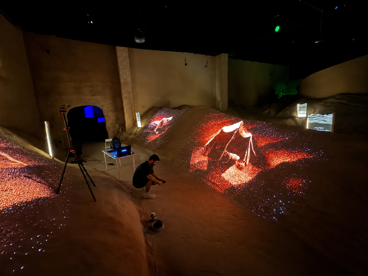 Projected media across irregular rock-like scenic surfaces at Ghar Thawr.