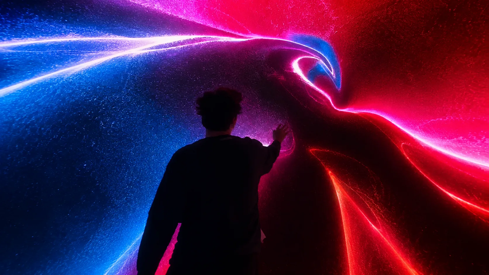 Visitor interacting with a red and blue generative visual on the media wall.