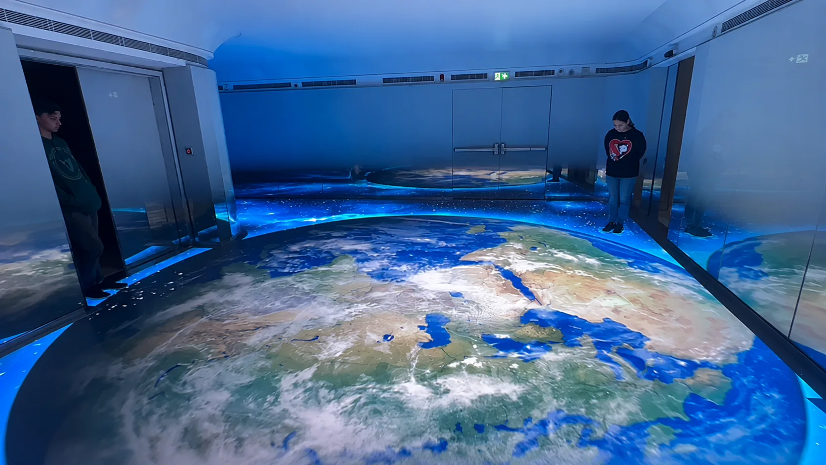 Visitors standing on the interactive LED floor as it displays a view of Earth.